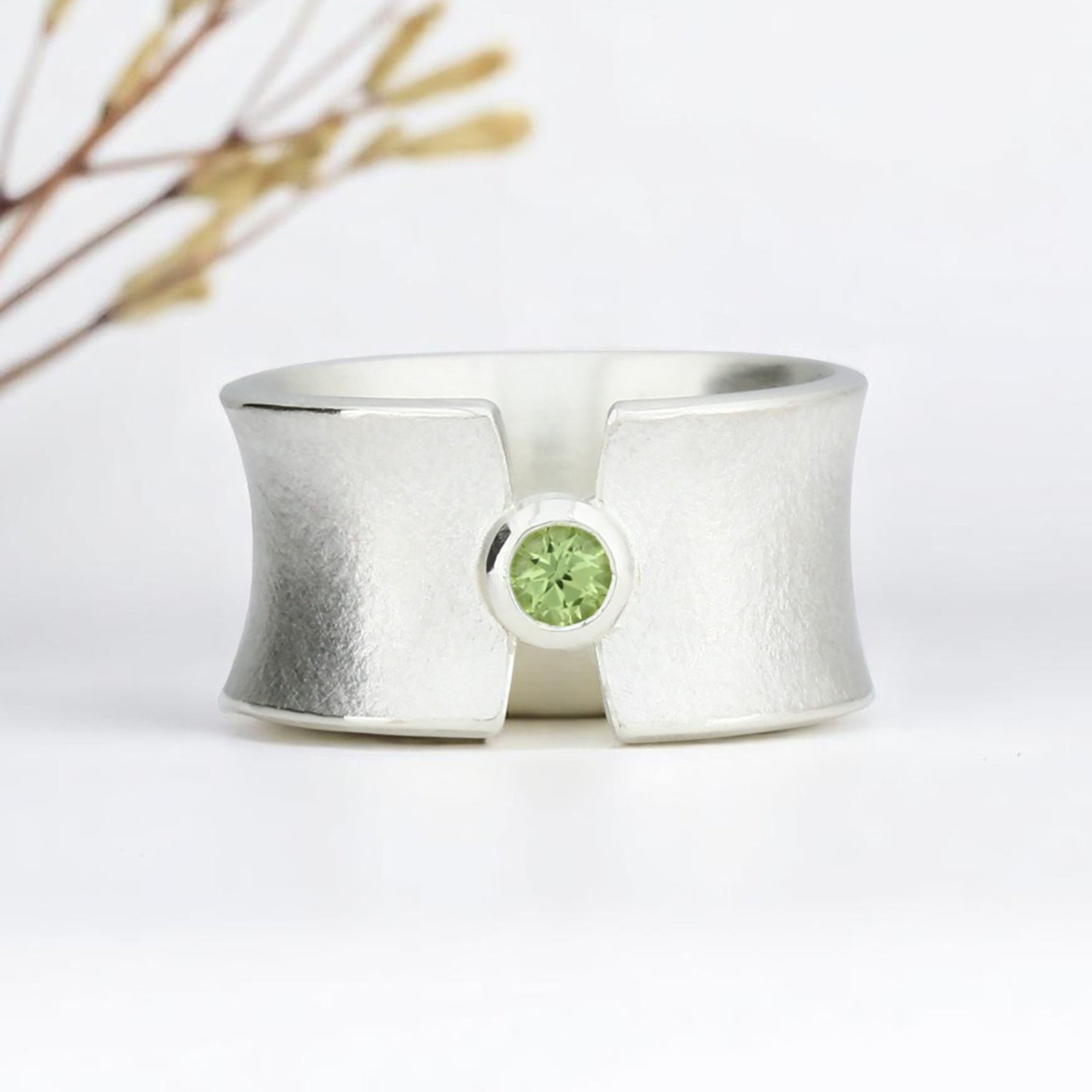 Breiter Silberring mit Peridot. Aufgespannte Form.