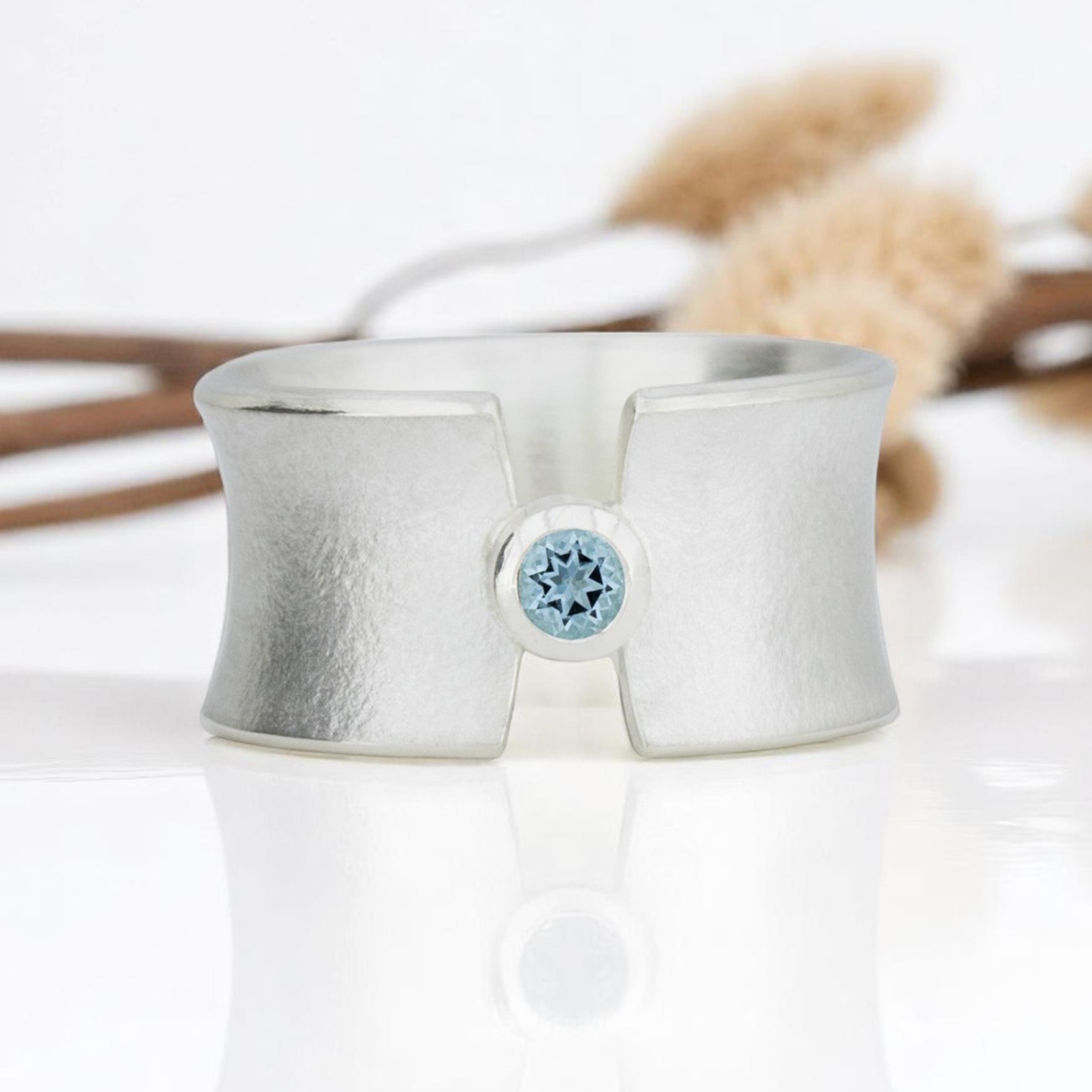 Breiter, aufgespannter Silberring mit blauem Topas.