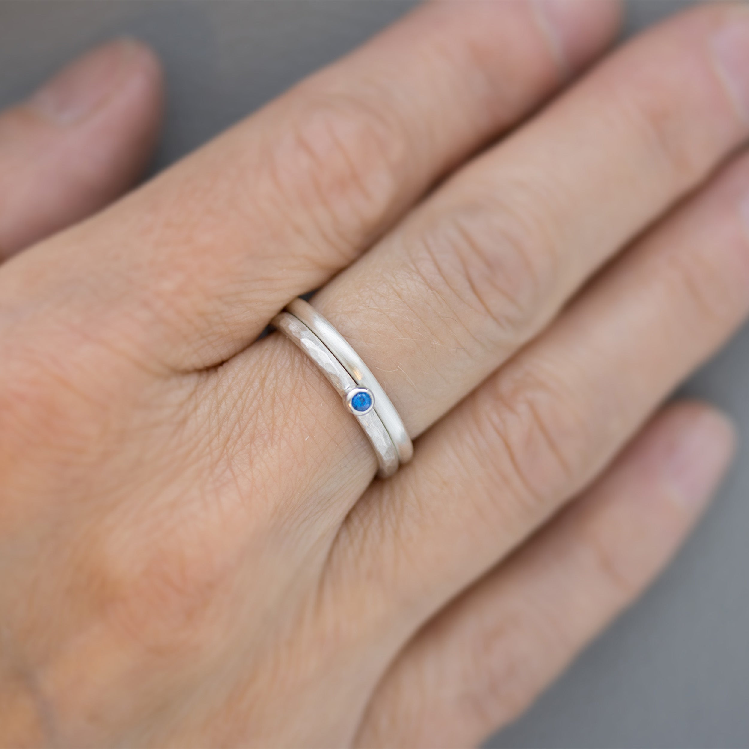 Ringset mit dunkelblauem Topas als Beispiel an einem Finger um das Größenverhältnis darzustellen. 