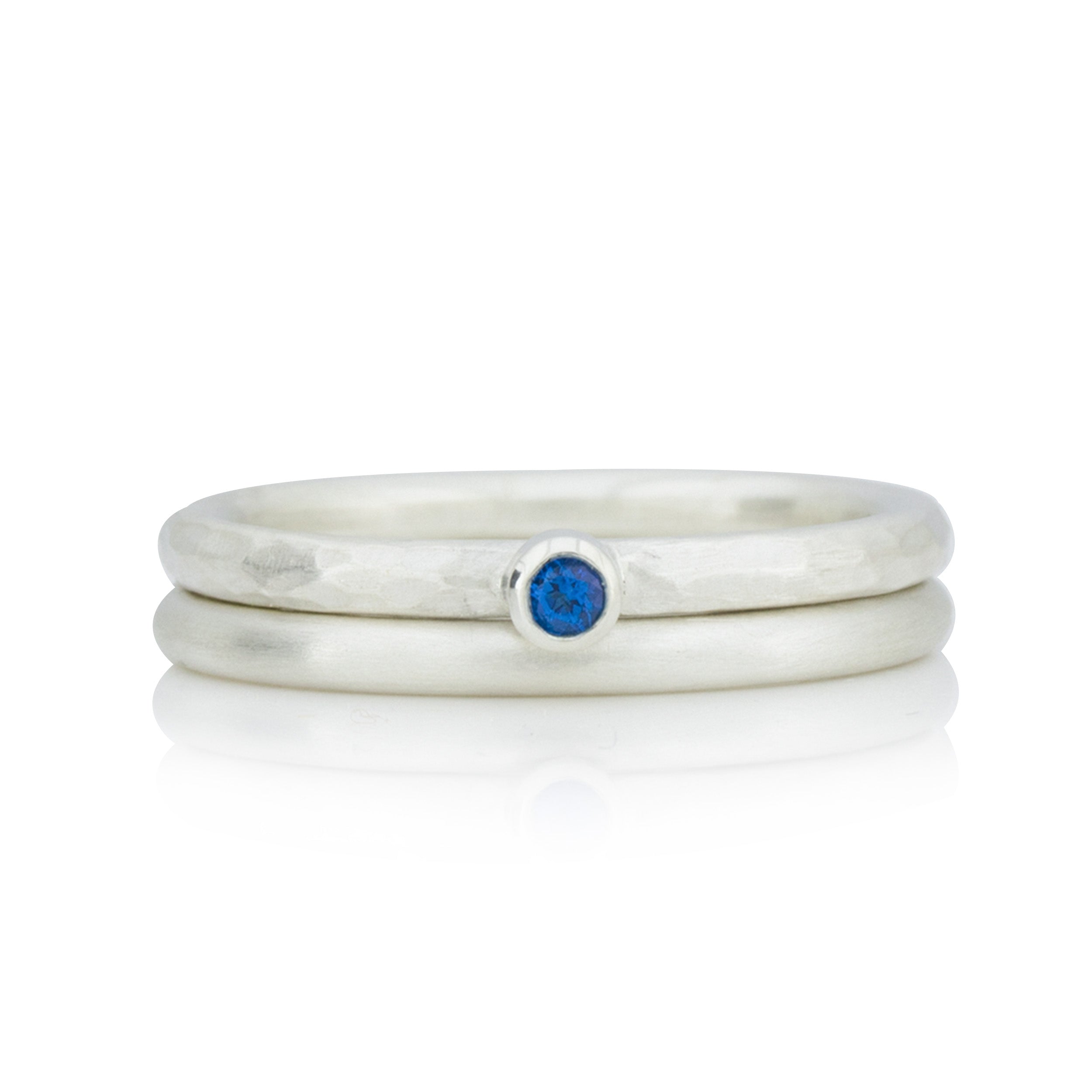 Ringset bestehend aus zwei Silberringen. Ein Ring mit dunkelblauem Topas und geschmiedeter Ringschiene. Ein zweiter Ring mit glatter und mattierter Oberfläche. Die Materialstärke der jeweiligen Ringschiene beträgt 2 mm. 