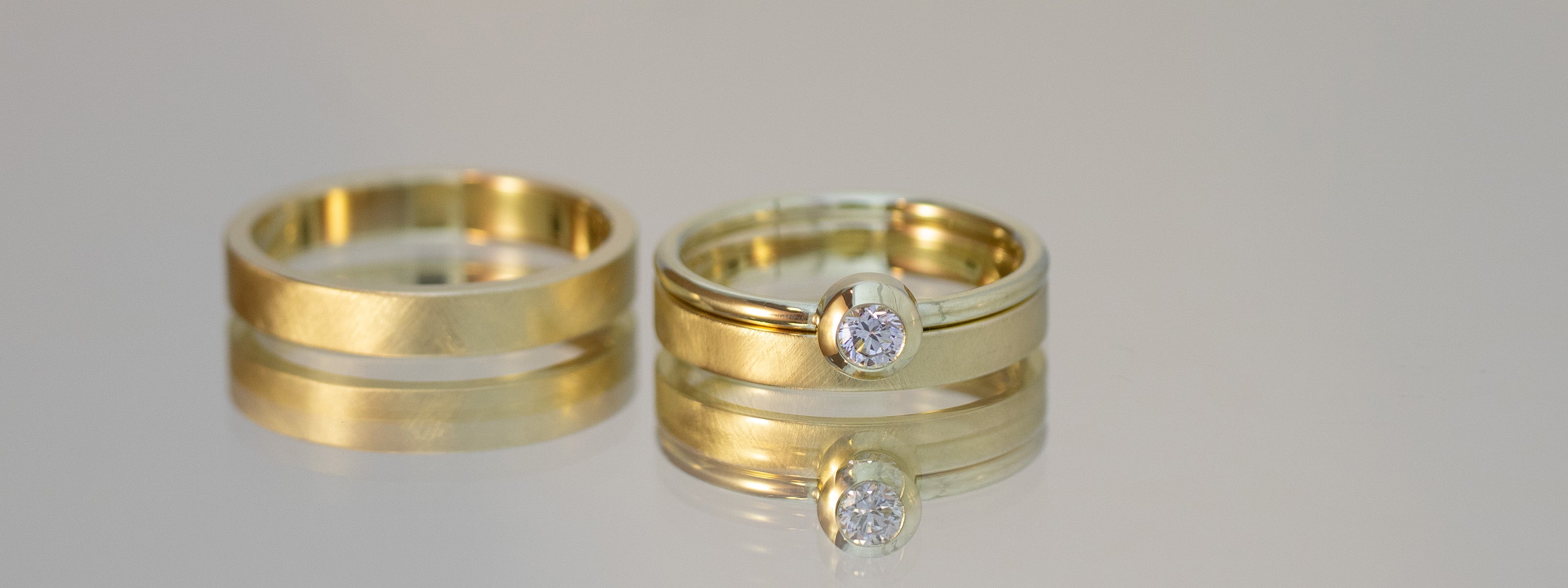 Trauringpaar in Gelbgold. Damenringset mit Vorsteckring, Diamantring. Der Verlobungsring ist handgefertigt und sehr puristisch. 