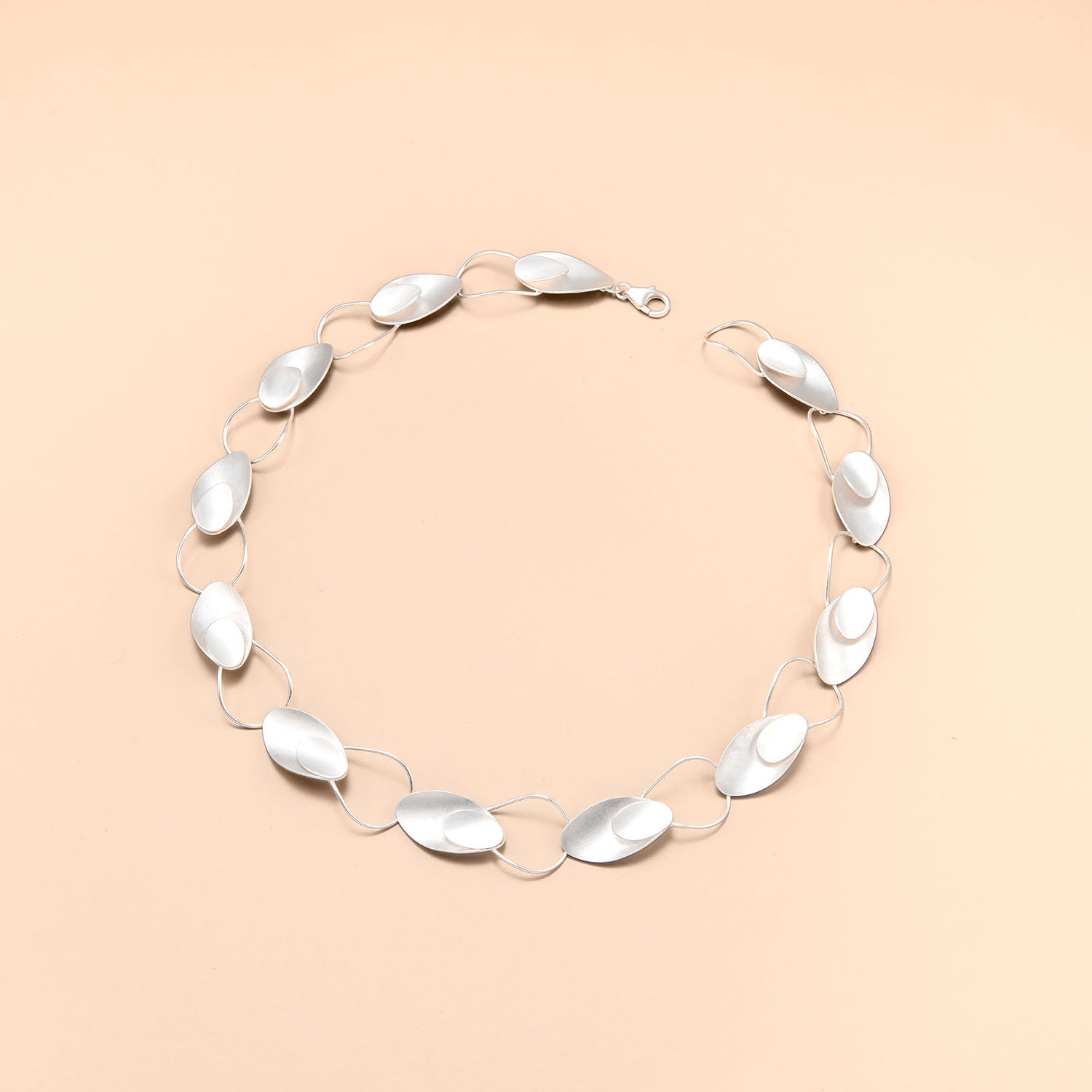 Collier aus Silber mit Ösen und ovalen Silberelementen. Diese wechseln sich regelmäßig und es entsteht eine rhythmische Struktur. Hersteller ist die schweizer Firma Kelim Schmuckdesign.