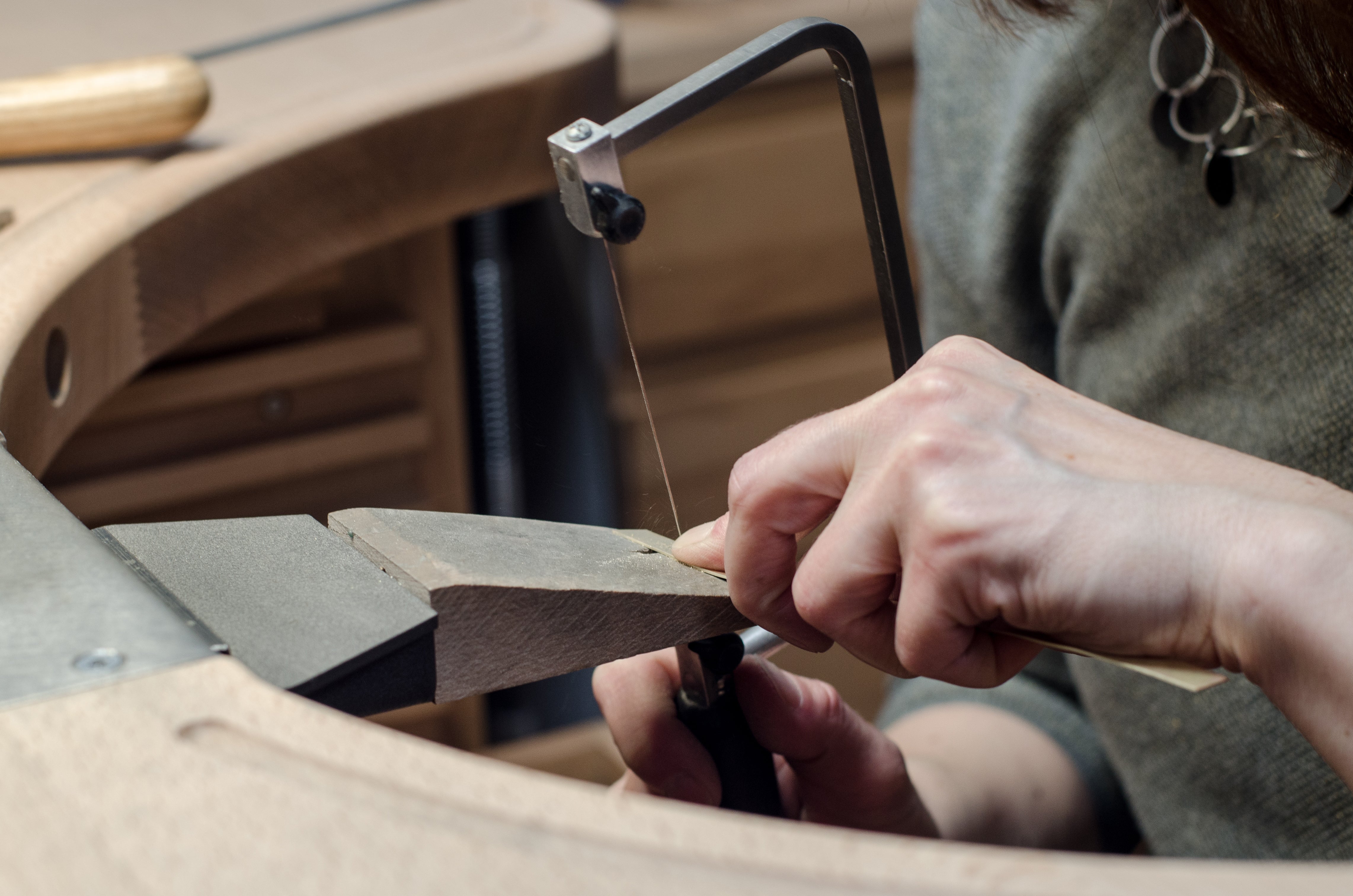 Handarbeit in Goldschmiedewerkstatt. Sägen mit Sägebogen. Hände bei der Arbeit. 